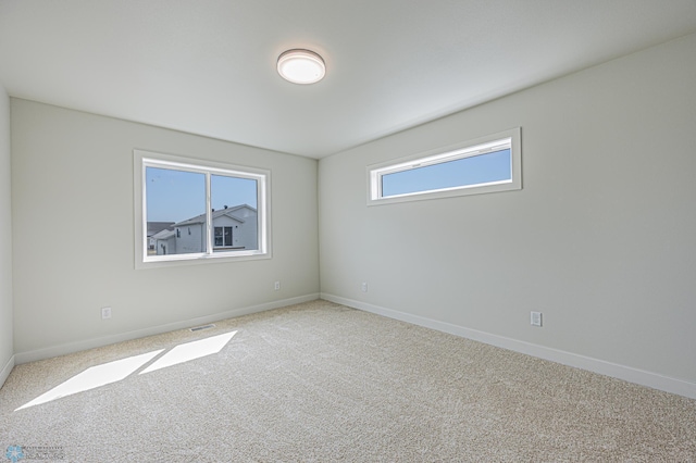 carpeted spare room featuring baseboards
