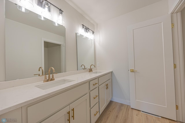 bathroom with double vanity, wood finished floors, and baseboards