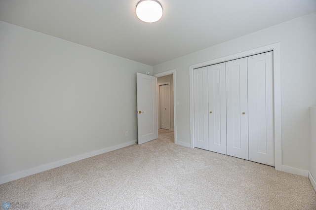 unfurnished bedroom featuring carpet floors, baseboards, and a closet