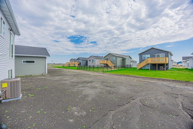 view of yard with a residential view, central air condition unit, stairs, and a deck