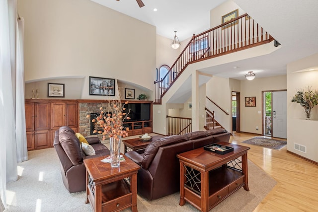 12800 Garrett Ct, Apple Valley, MN 55124 - living area featuring a stone fireplace, stairs, light wood-style floors, ceiling fan, and a towering ceiling
