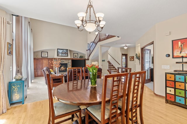 12800 Garrett Ct, Apple Valley, MN 55124 - dining area featuring light wood-style floors, a fireplace, stairs, and a chandelier