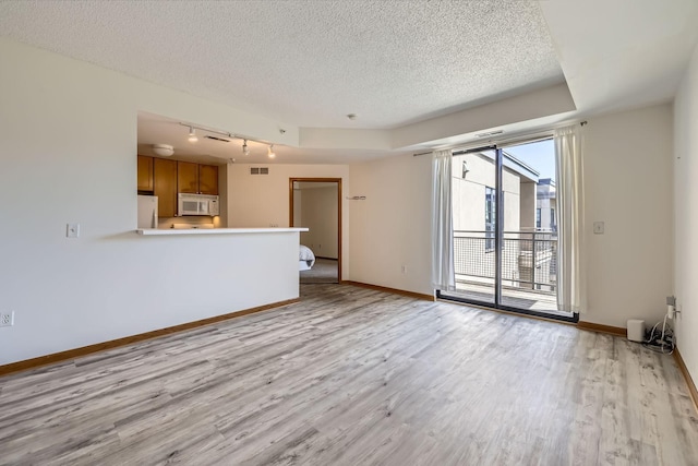 820 Emerald St Unit 402, Saint Paul, MN 55114 - unfurnished living room with rail lighting, light wood-type flooring, a textured ceiling, and baseboards