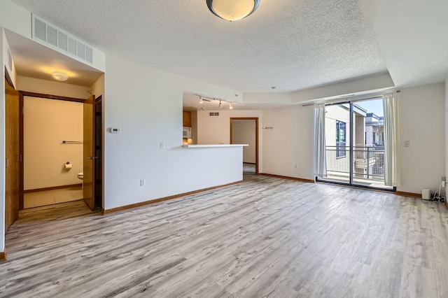 820 Emerald St Unit 402, Saint Paul, MN 55114 - unfurnished living room featuring a textured ceiling, wood finished floors, baseboards, and track lighting