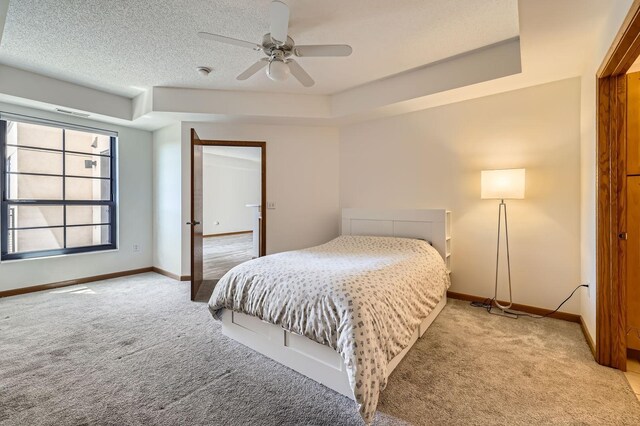 820 Emerald St Unit 402, Saint Paul, MN 55114 - bedroom featuring light carpet, baseboards, ceiling fan, a tray ceiling, and a textured ceiling