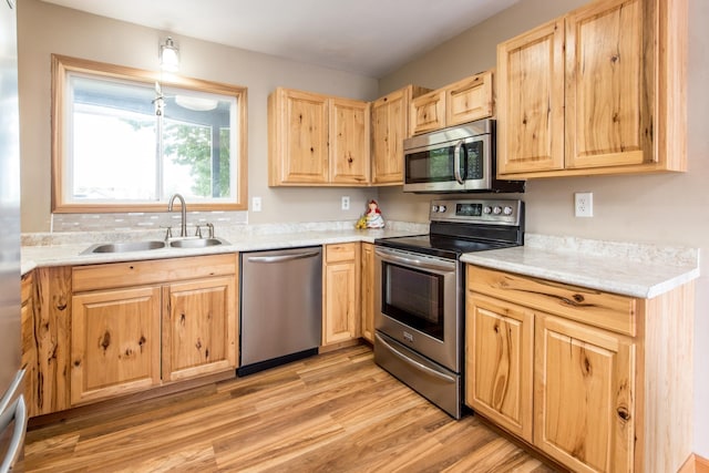 kitchen with light wood-type flooring, stainless steel appliances, light brown cabinetry, and a sink