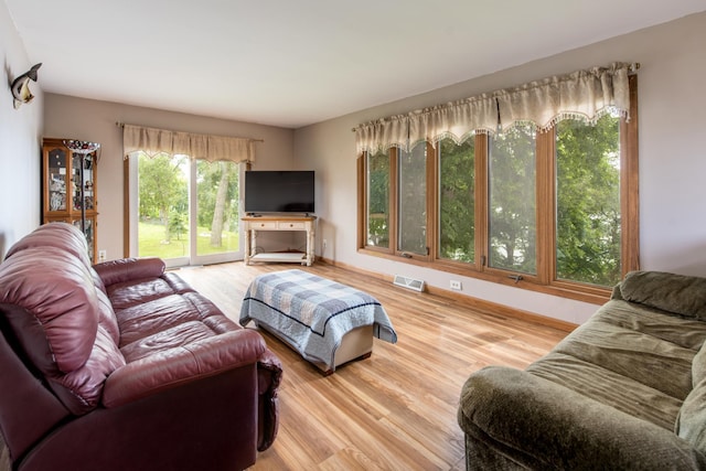 living area with baseboards, visible vents, and wood finished floors