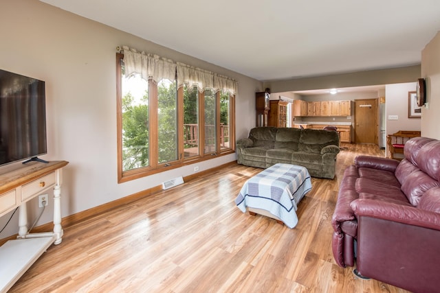 living room featuring baseboards, light wood-style flooring, and visible vents