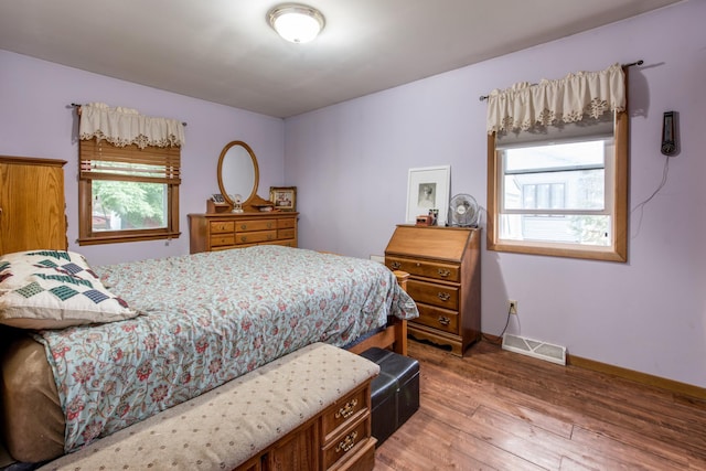 bedroom featuring light wood finished floors, visible vents, and baseboards