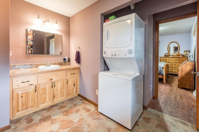 ensuite bathroom with baseboards, ensuite bath, vanity, and stacked washer and clothes dryer