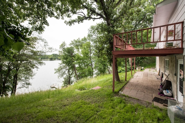 view of yard with a deck with water view and a patio