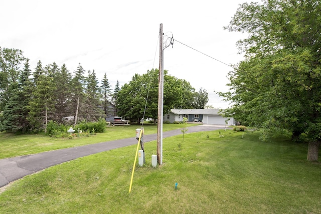 view of yard featuring aphalt driveway and a garage