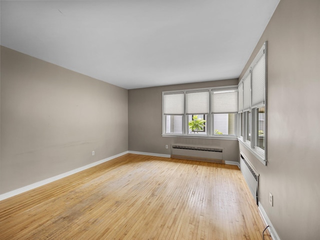 517 Olive St S, Waconia, MN 55387 - spare room featuring radiator, an AC wall unit, and light wood-type flooring