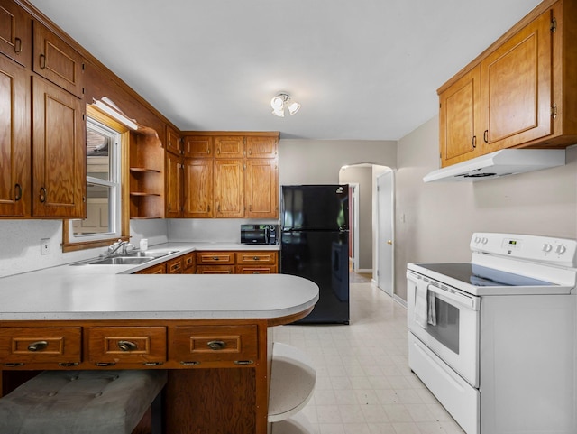 517 Olive St S, Waconia, MN 55387 - kitchen with white electric range oven, freestanding refrigerator, under cabinet range hood, light countertops, and arched walkways