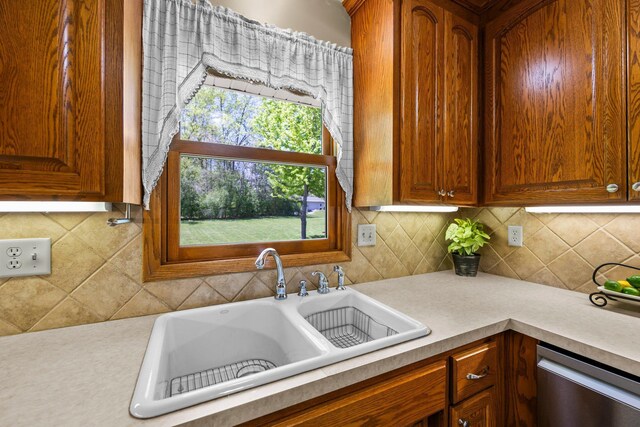 kitchen featuring a sink, stainless steel dishwasher, light countertops, and decorative backsplash