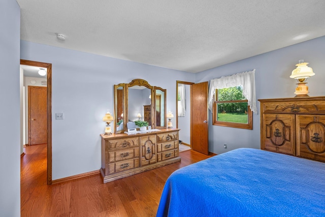 bedroom featuring wood finished floors, a textured ceiling, and baseboards
