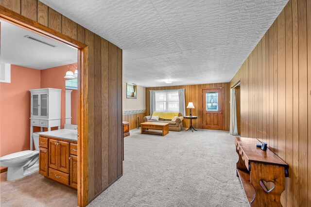 carpeted living area with wood walls and a textured ceiling
