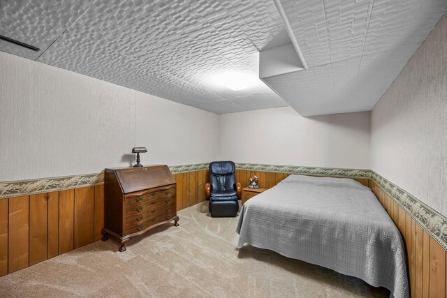 bedroom featuring carpet flooring, wood walls, and wainscoting