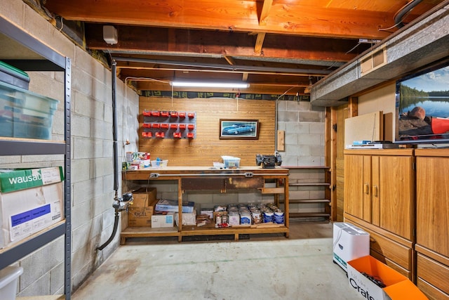 unfinished below grade area with concrete block wall and a workshop area