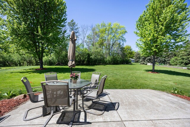 view of patio / terrace featuring outdoor dining space and view of wooded area