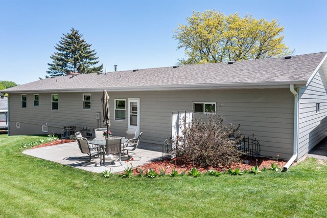 rear view of property featuring a patio area, a yard, and a shingled roof