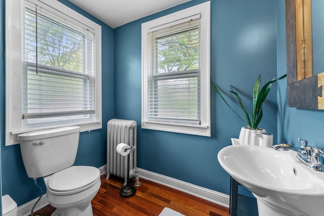 3100 29th Ave S, Minneapolis, MN 55406 - half bath featuring radiator, toilet, wood finished floors, baseboards, and a sink