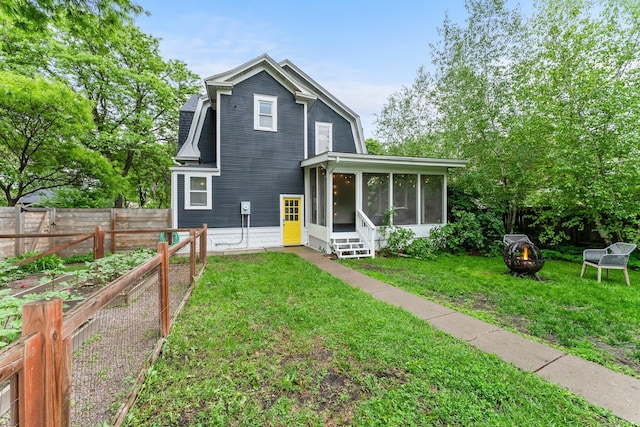 3100 29th Ave S, Minneapolis, MN 55406 - rear view of property featuring an outdoor fire pit, a sunroom, and a vegetable garden
