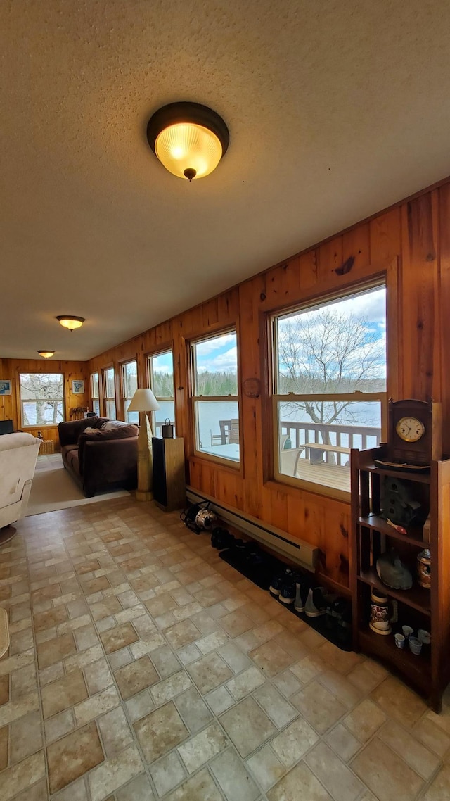 499 Tamarack Ct NE, Tenstrike, MN 56683 - living room featuring wooden walls, a baseboard heating unit, vaulted ceiling, a textured ceiling, and stone finish flooring