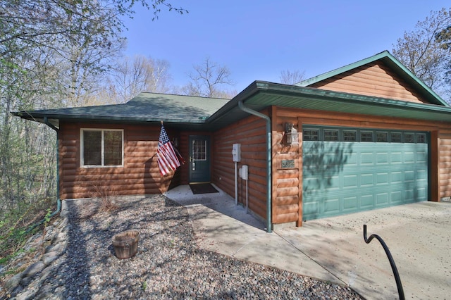 view of front of house featuring an attached garage, faux log siding, and concrete driveway