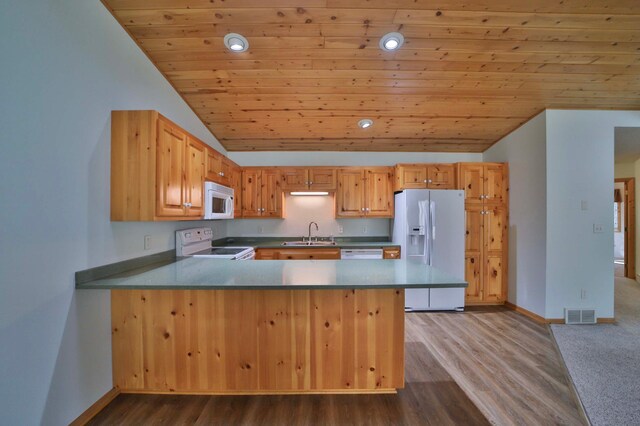 kitchen with white appliances, vaulted ceiling, a sink, a peninsula, and baseboards