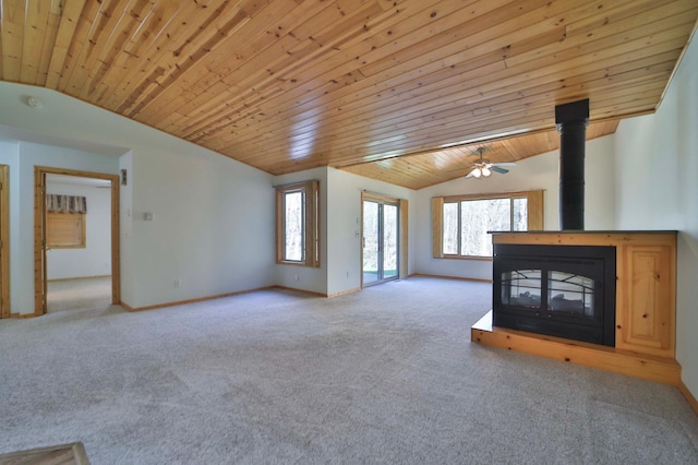 unfurnished living room with lofted ceiling, carpet, wood ceiling, a wood stove, and baseboards