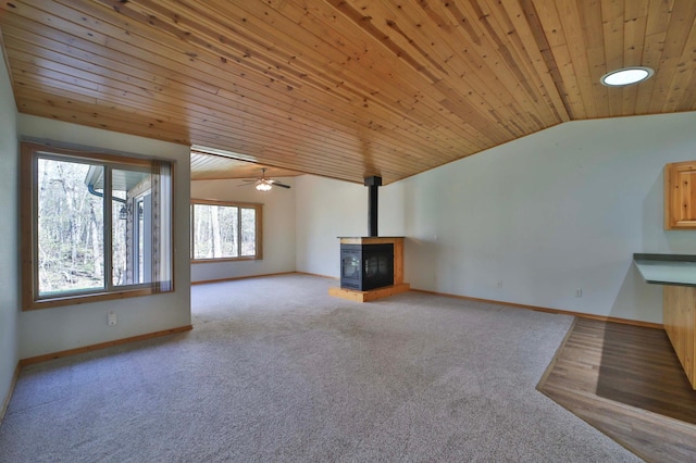 unfurnished living room with vaulted ceiling, wood ceiling, carpet flooring, ceiling fan, and baseboards