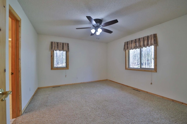 empty room featuring carpet floors, baseboards, a textured ceiling, and a ceiling fan