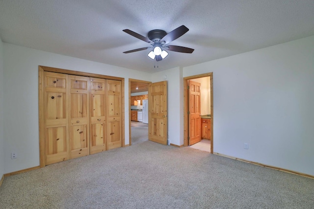 unfurnished bedroom with freestanding refrigerator, light colored carpet, ensuite bathroom, a ceiling fan, and baseboards
