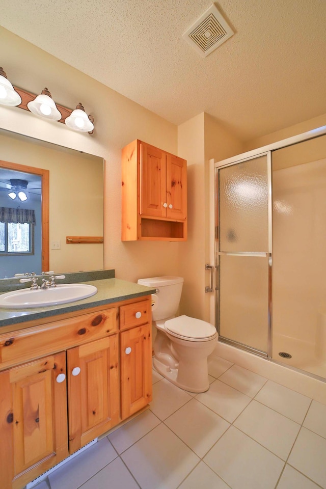 bathroom with toilet, tile patterned flooring, a shower stall, a textured ceiling, and vanity