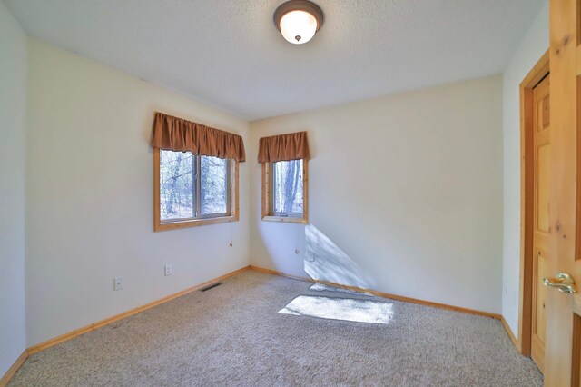 carpeted spare room featuring baseboards and a textured ceiling