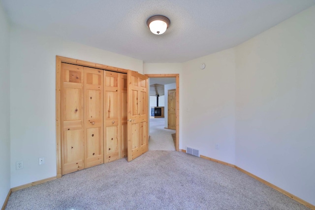 unfurnished bedroom with carpet floors, baseboards, and a textured ceiling