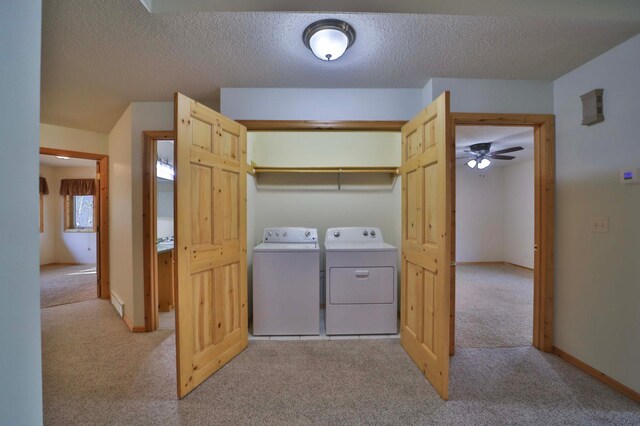clothes washing area with carpet, washer and clothes dryer, a ceiling fan, a textured ceiling, and baseboards