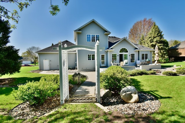 rear view of property featuring a lawn, a patio area, and a shingled roof