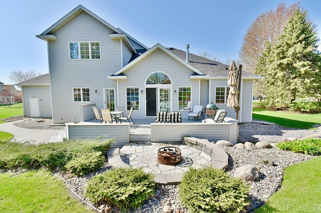 rear view of house with an outdoor fire pit, a deck, a patio, and roof with shingles
