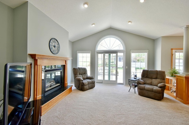 living room featuring lofted ceiling, carpet flooring, a glass covered fireplace, and plenty of natural light