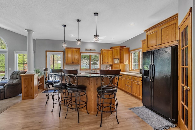 1609 26th St SE, Saint Cloud, MN 56304 - kitchen featuring black refrigerator with ice dispenser, ornate columns, plenty of natural light, open floor plan, and a textured ceiling