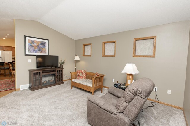 carpeted living area featuring vaulted ceiling and baseboards