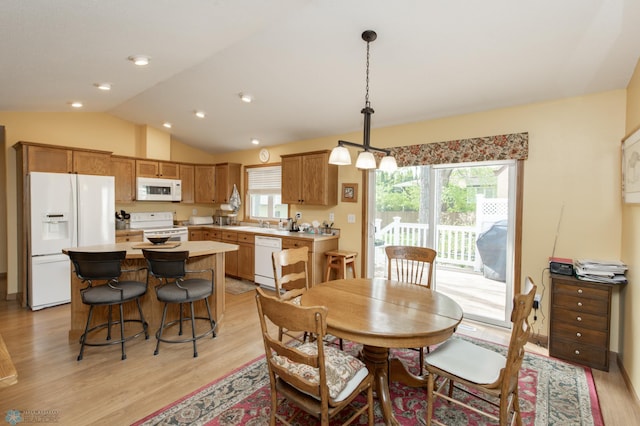 dining space featuring light wood-type flooring and vaulted ceiling
