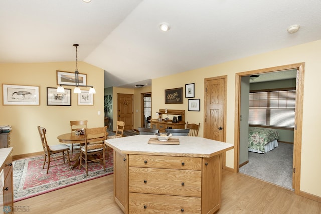 kitchen featuring light wood finished floors, light countertops, vaulted ceiling, baseboards, and a kitchen island