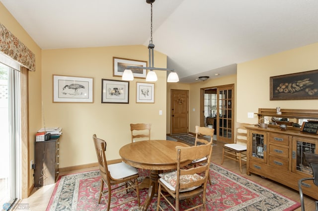 dining room featuring wood finished floors, lofted ceiling, and baseboards