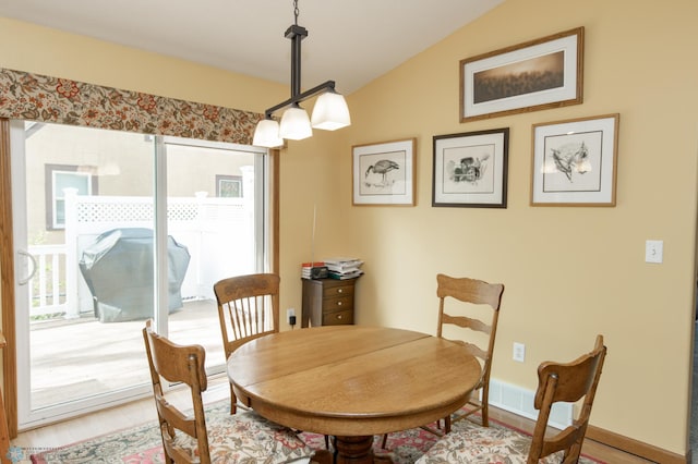 dining room with vaulted ceiling and light wood-style floors
