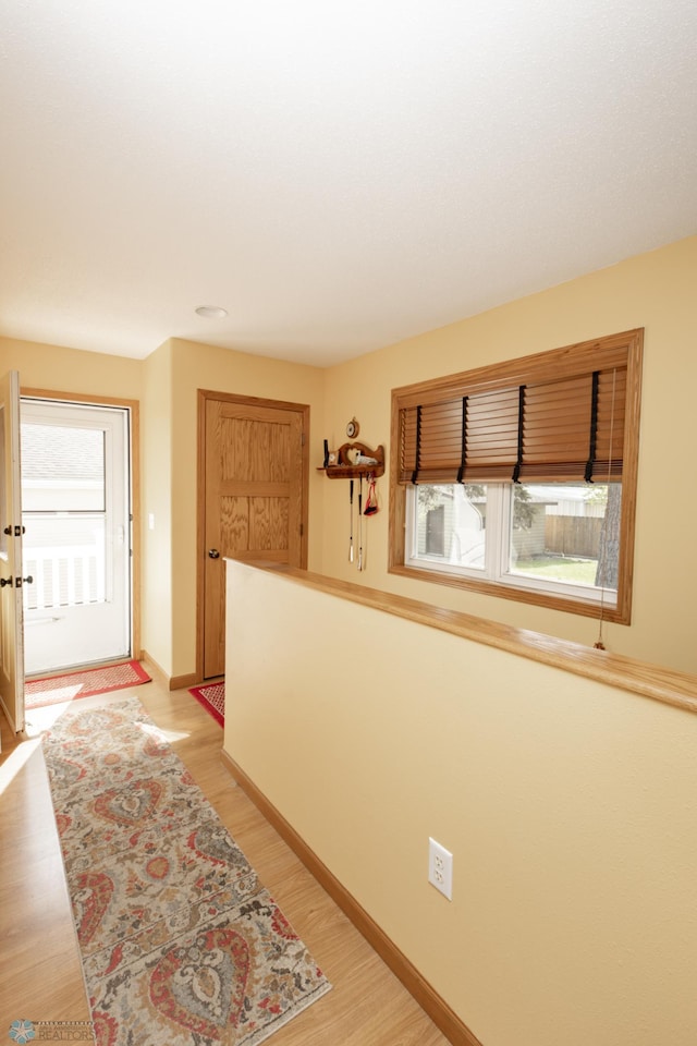 corridor featuring light wood finished floors and baseboards