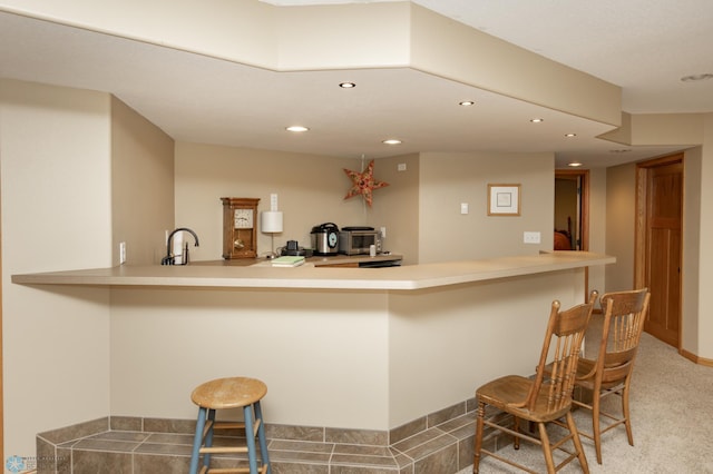 kitchen featuring recessed lighting, a kitchen breakfast bar, a sink, a peninsula, and light countertops