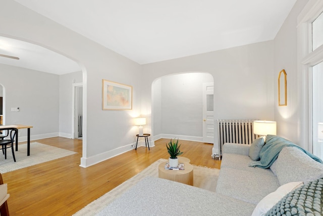 1925 Glenwood Ave, Minneapolis, MN 55405 - living area featuring arched walkways, light wood-style floors, radiator heating unit, and baseboards